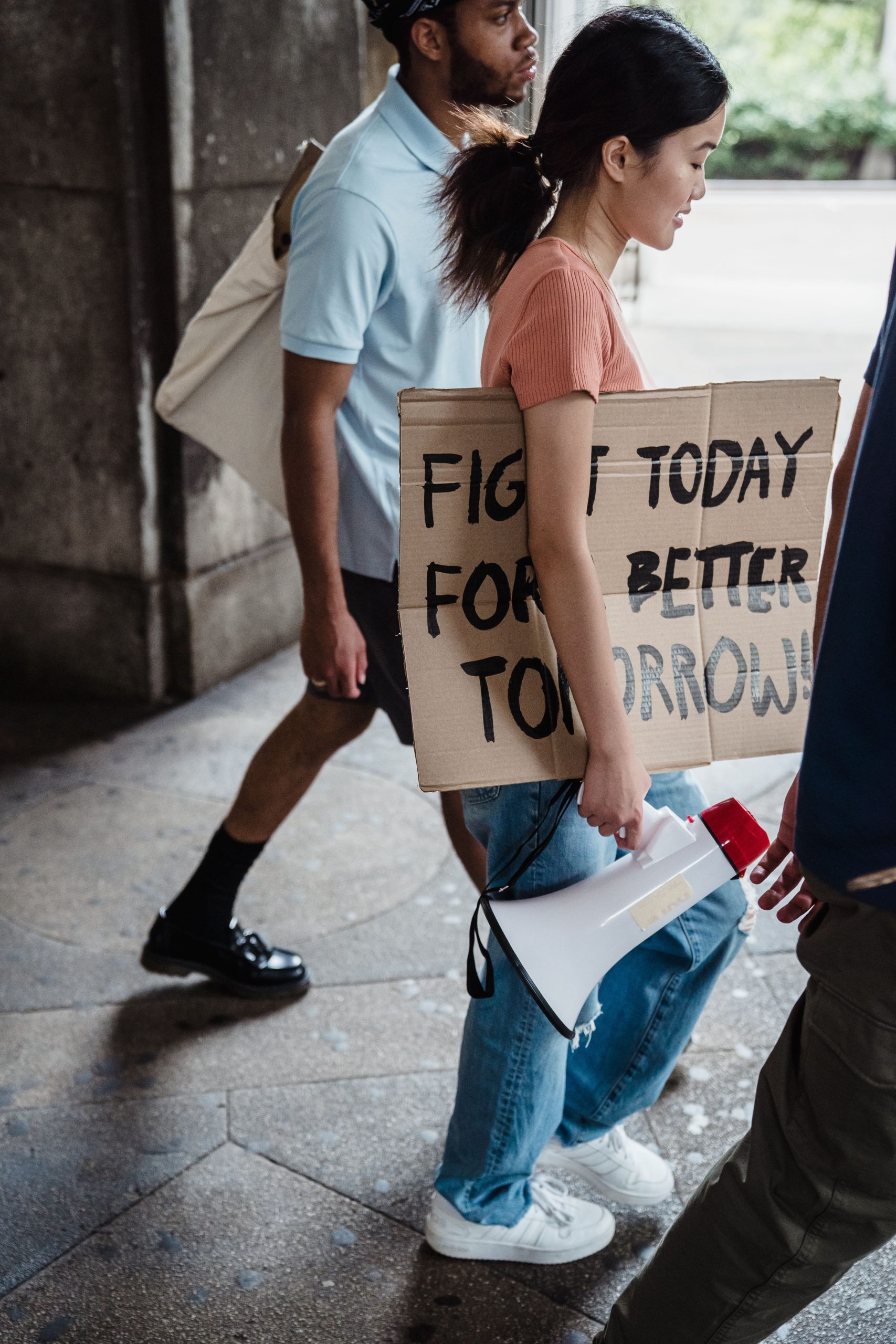 Diverse group of activists marching in protest with signs and a megaphone on a city street.